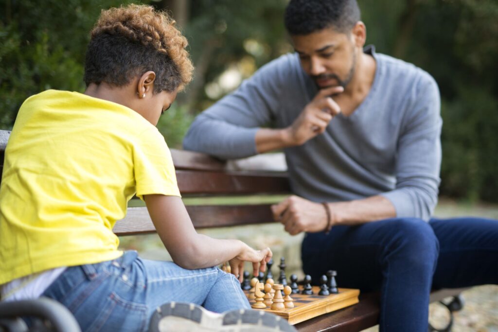 Boy bonding with an adult male through a game of chess.
